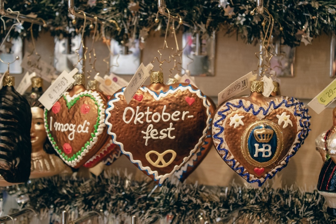 Traditionella dekorerade pepparkakshjärtan (Lebkuchenherzen) som hänger som prydnader, med ett som tydligt visar texten 'Oktoberfest' i vit glasyr, typiska festivalminnessaker med bayersk stil.